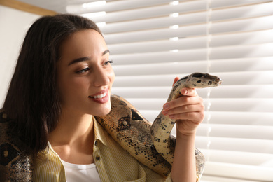 Young woman with her boa constrictor at home. Exotic pet