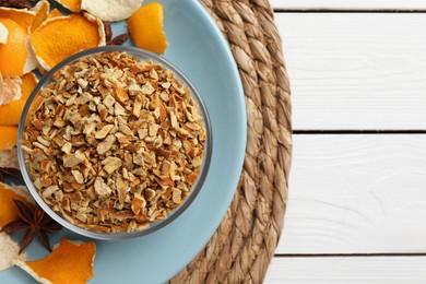 Photo of Bowl of dried orange zest seasoning, fresh peel and anise on white wooden table, top view. Space for text