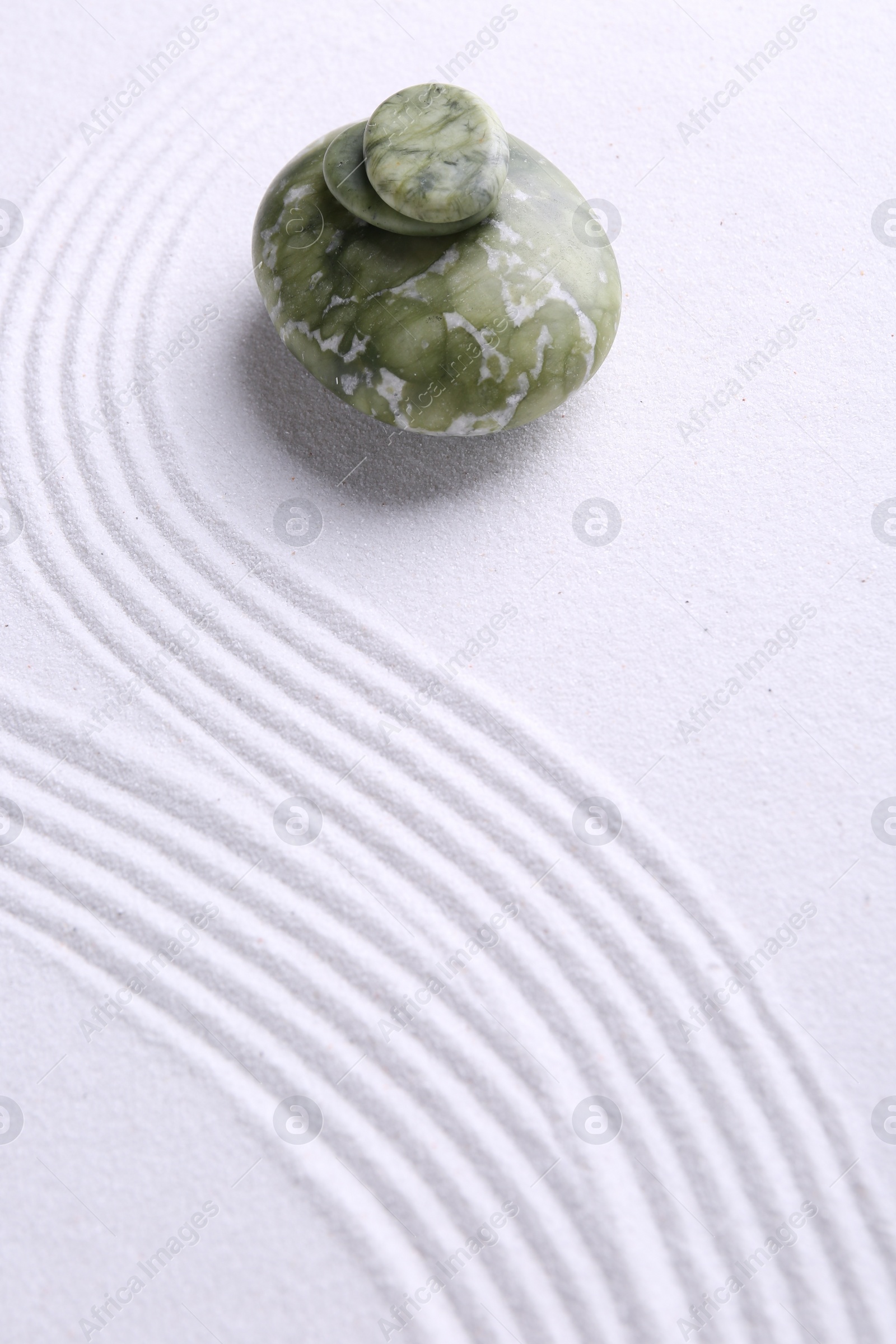 Photo of Zen garden stones on white sand with pattern. Space for text