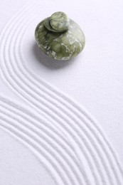 Photo of Zen garden stones on white sand with pattern. Space for text