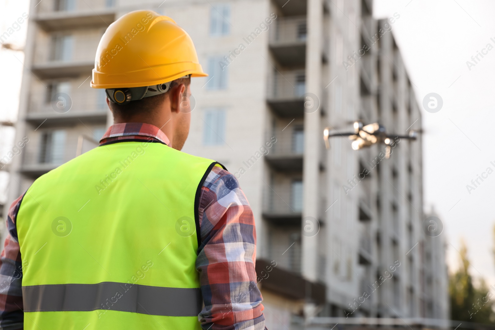 Photo of Builder operating drone with remote control at construction site. Aerial survey