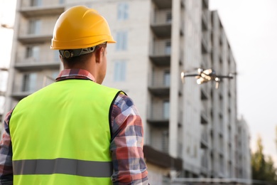 Builder operating drone with remote control at construction site. Aerial survey