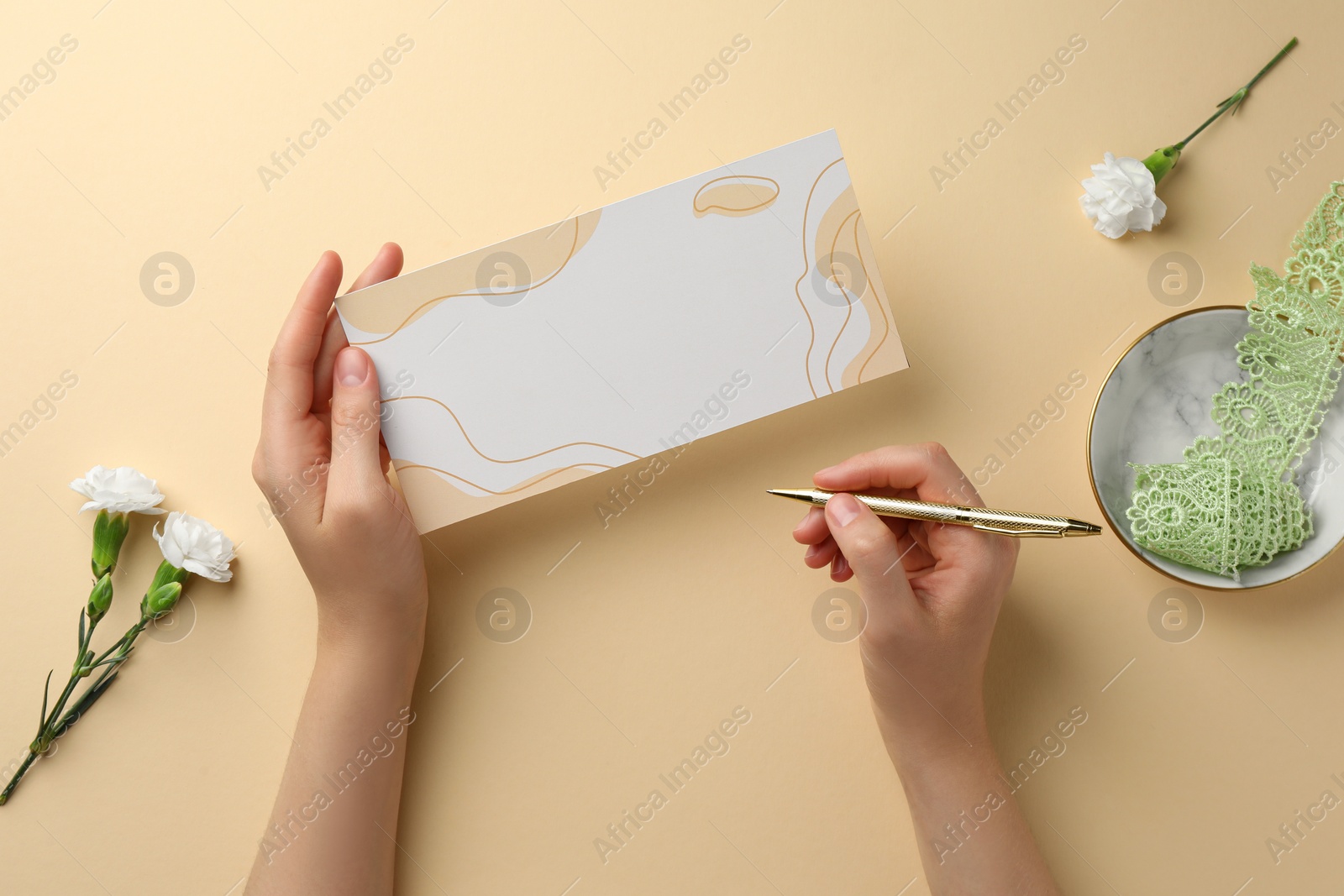 Photo of Woman holding blank invitation card on beige background, top view. Space for text