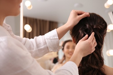 Stylist working with client in salon, making hairstyle