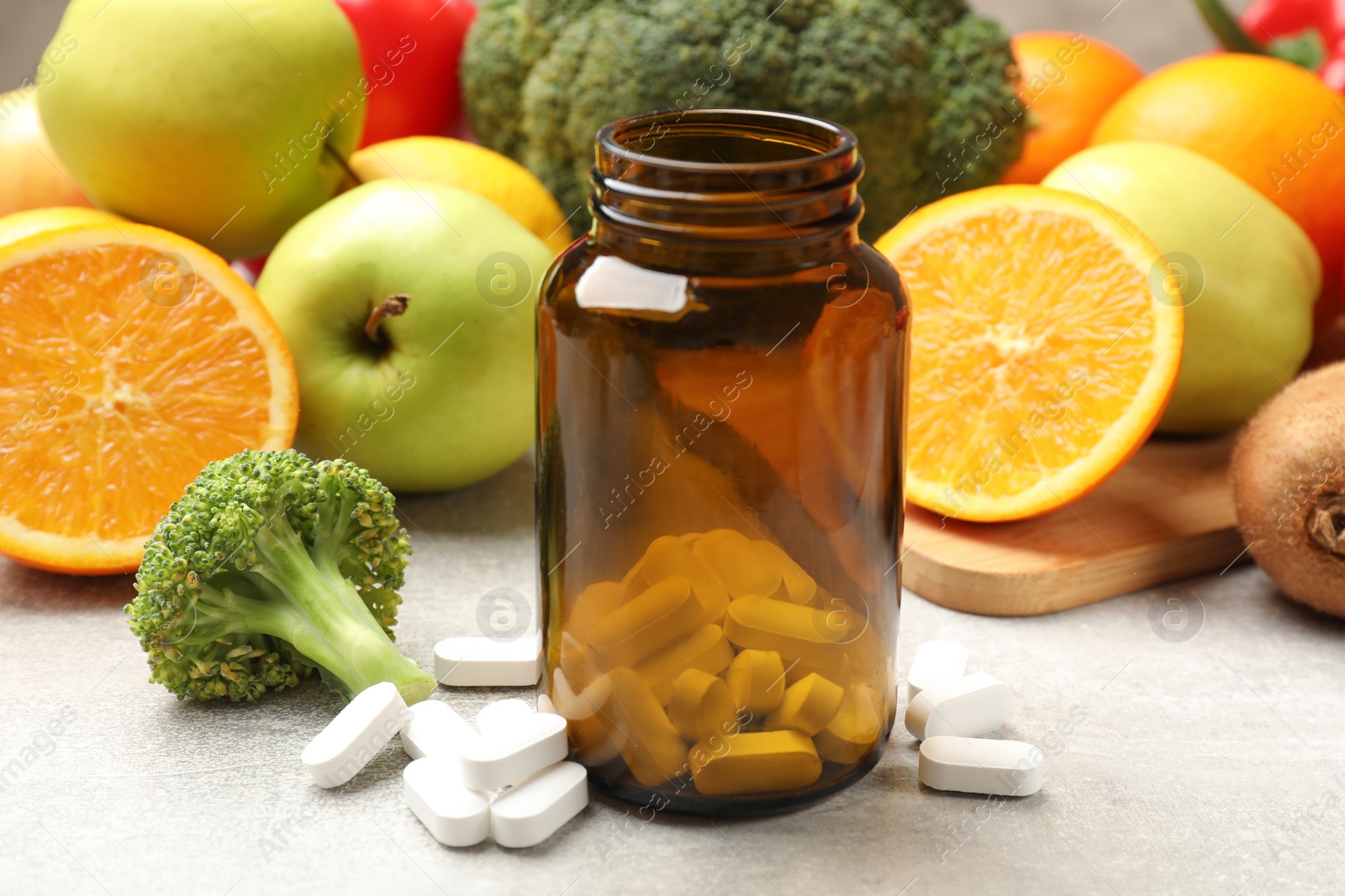 Photo of Dietary supplements. Bottle, pills and food products on grey table