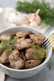 Photo of Tasty fried chicken liver with dill and fork on grey table, closeup
