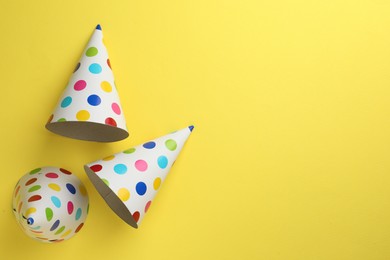 Photo of Beautiful party hats on yellow background, top view. Space for text