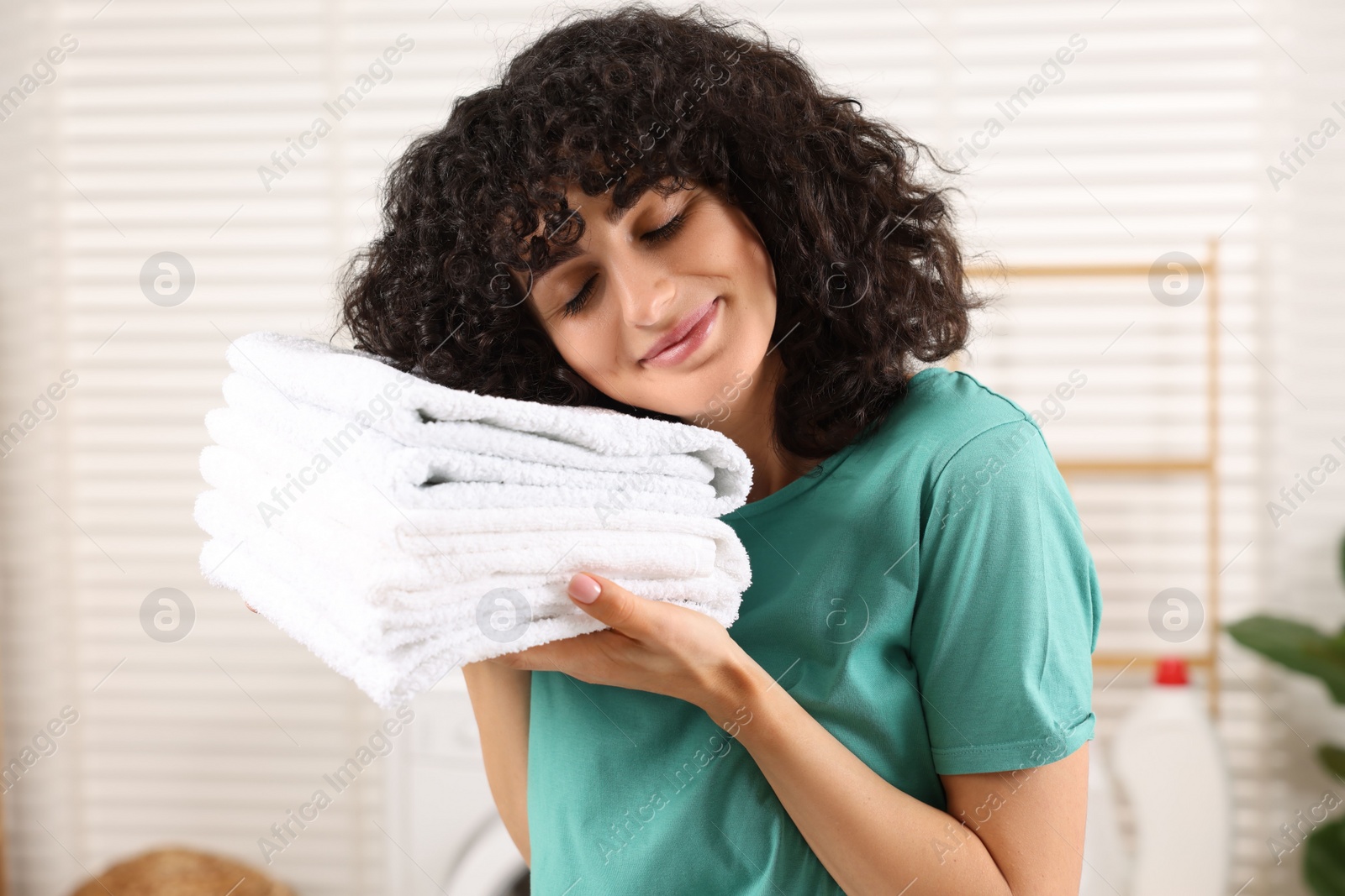 Photo of Beautiful woman with clean laundry at home