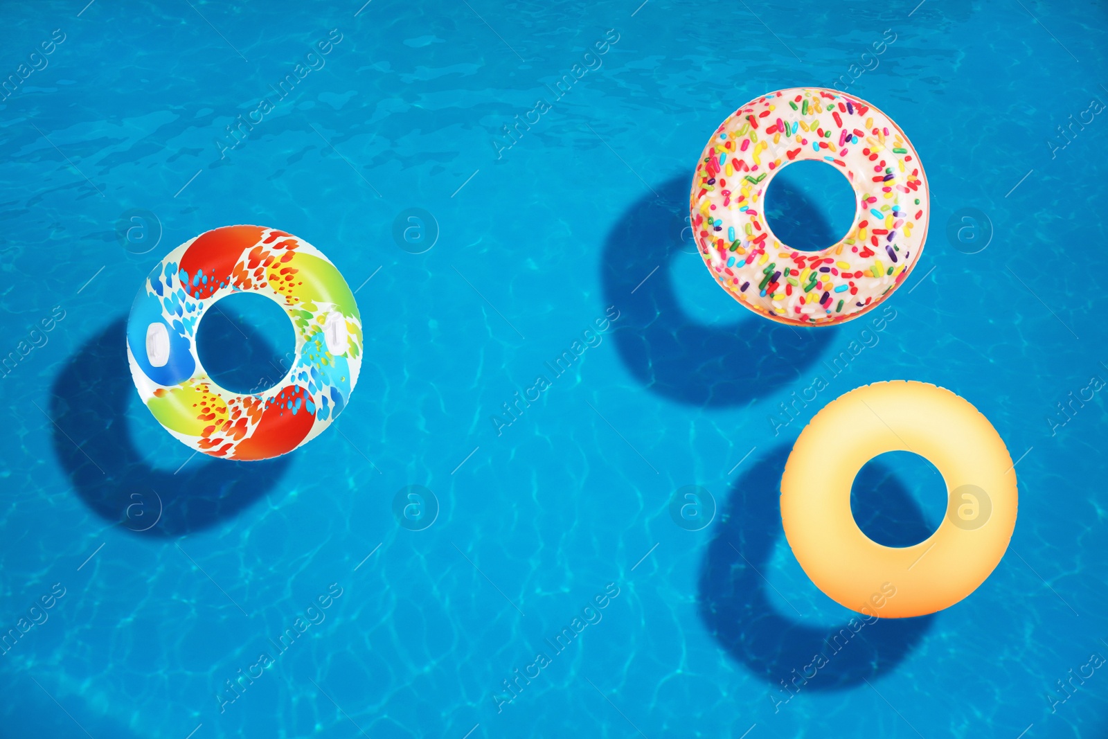 Image of Different inflatable rings floating in swimming pool, top view