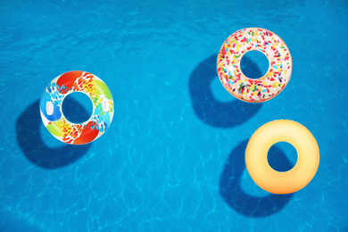 Image of Different inflatable rings floating in swimming pool, top view