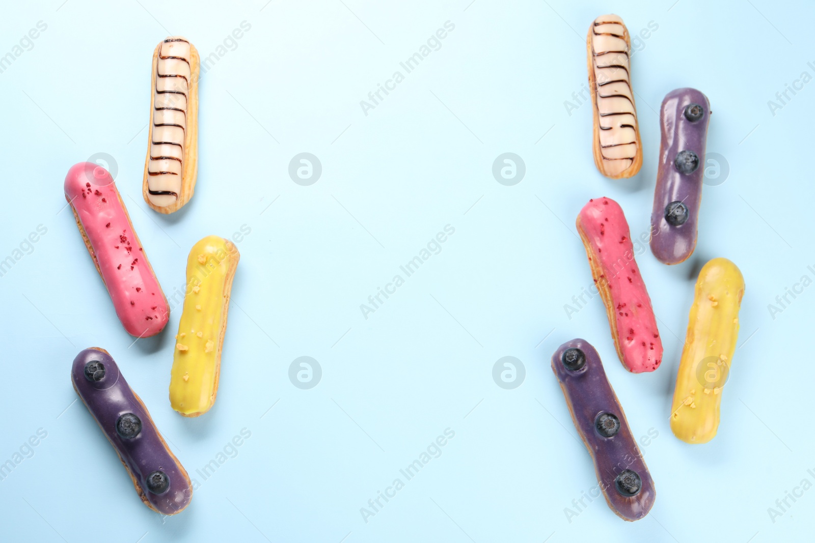 Photo of Delicious eclairs covered with glaze on light blue background, top view. Space for text