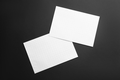 Photo of White paper envelopes on black background, flat lay