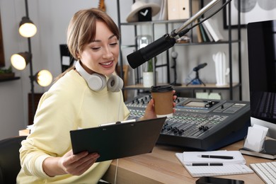 Photo of Woman with cup of coffee working as radio host in modern studio