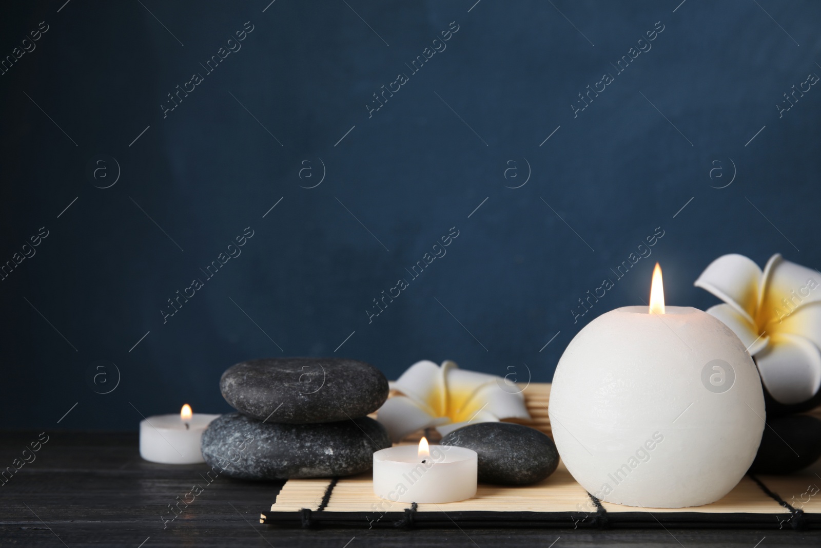 Photo of Spa stones, candles and flowers on table, space for text