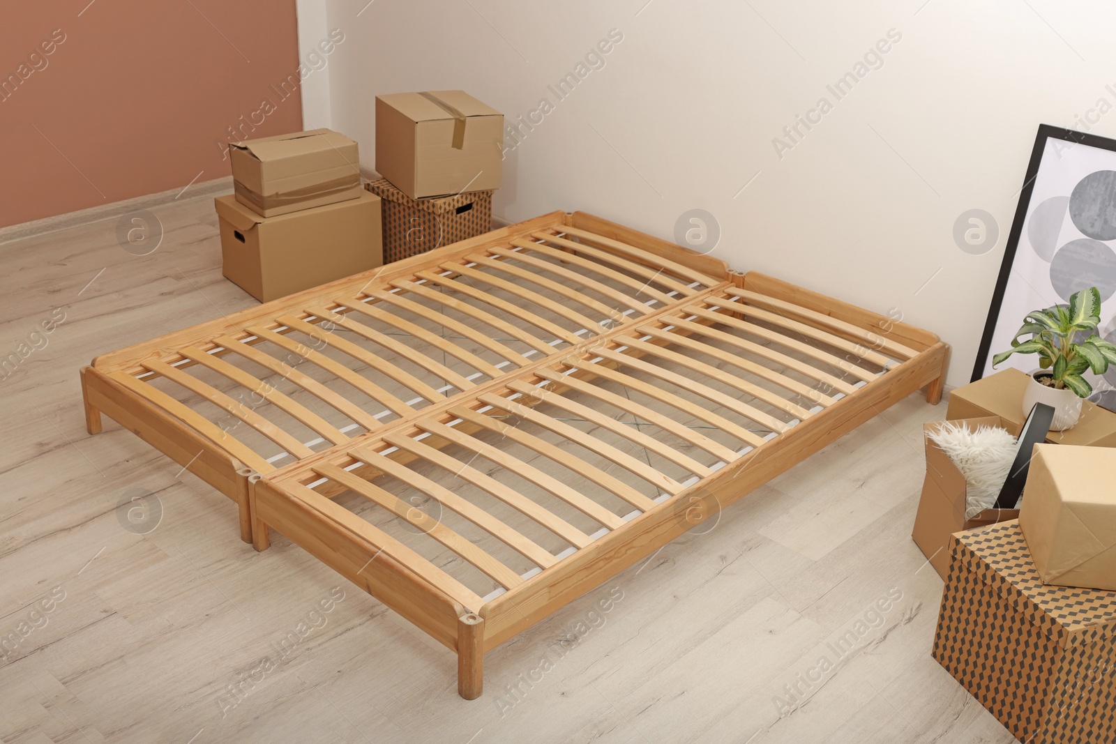 Photo of Wooden bed frame and cardboard boxes on floor in room