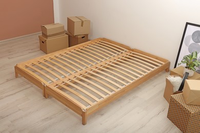 Photo of Wooden bed frame and cardboard boxes on floor in room