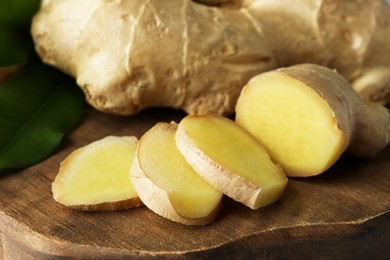 Fresh ginger with leaves on wooden board, closeup