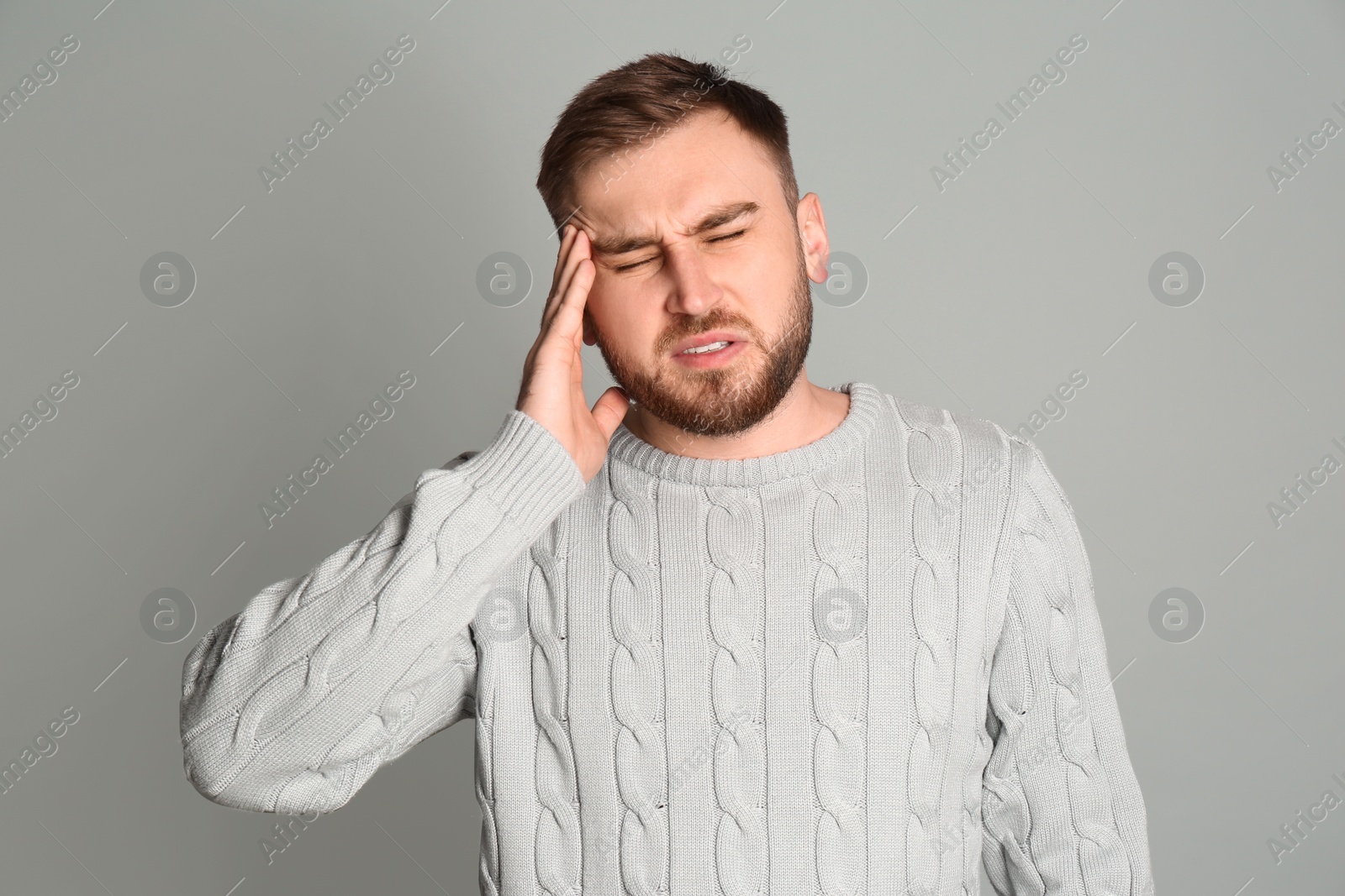 Photo of Man suffering from migraine on grey background