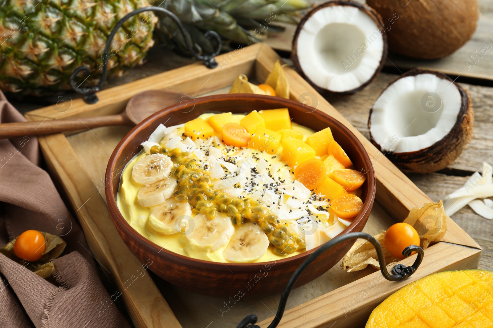 Photo of Tasty smoothie bowl with fresh fruits served on wooden table