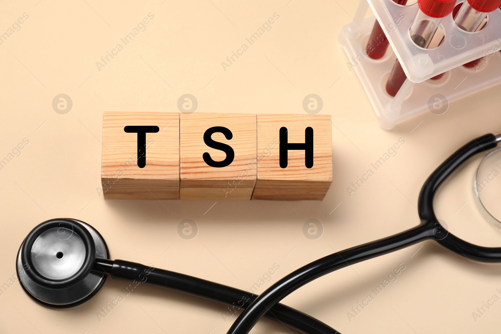 Photo of Endocrinology. Stethoscope, wooden cubes with thyroid hormones and blood samples in test tubes on beige background