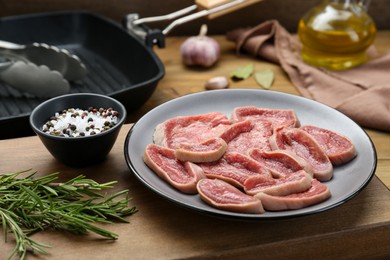 Photo of Raw beef tongue pieces, spices and rosemary on wooden board