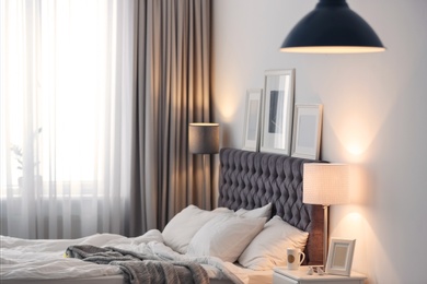 Modern room interior with comfortable bed and stylish lamp