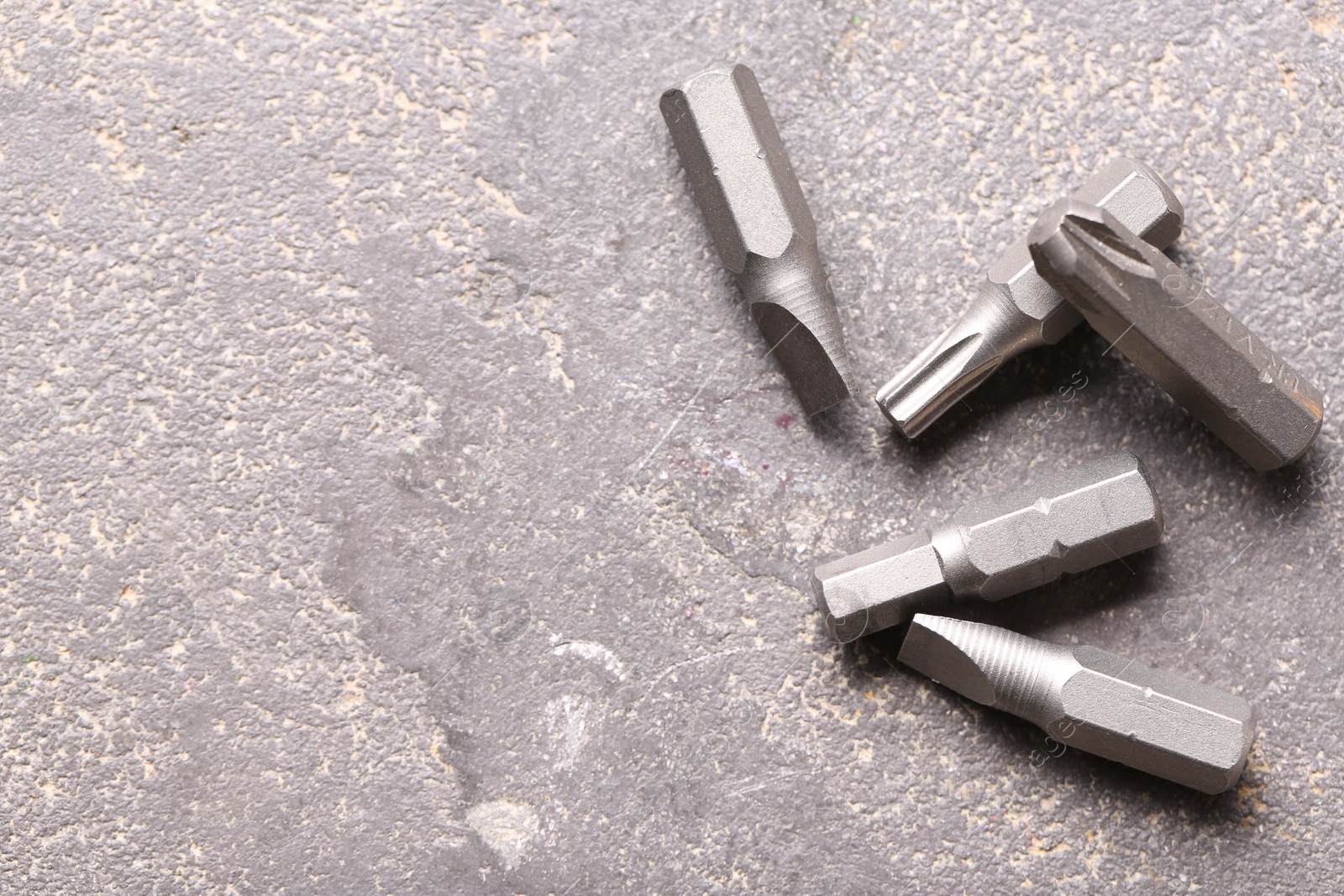 Photo of Different screwdriver bits on grey table, top view. Space for text