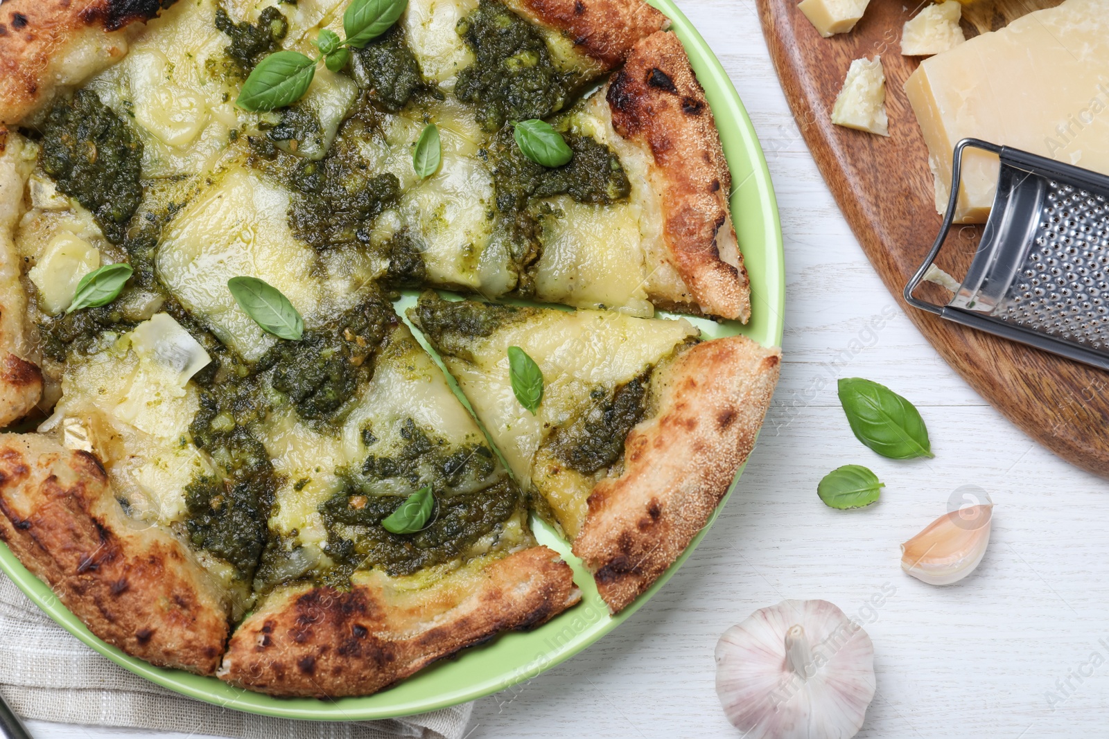 Photo of Delicious pizza with pesto, cheese and basil served on white wooden table, flat lay