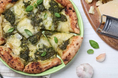 Delicious pizza with pesto, cheese and basil served on white wooden table, flat lay