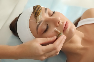Young woman receiving snail facial massage in spa salon, closeup