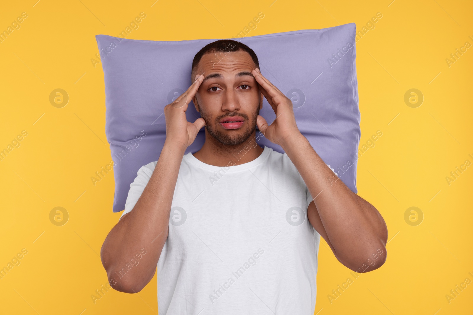 Photo of Tired man with pillow on orange background. Insomnia problem