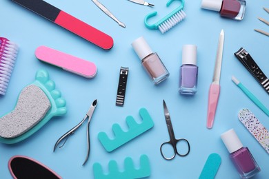 Set of pedicure tools on light blue background, flat lay