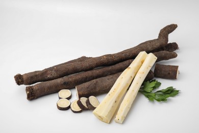 Photo of Fresh raw salsify roots and parsley on white background