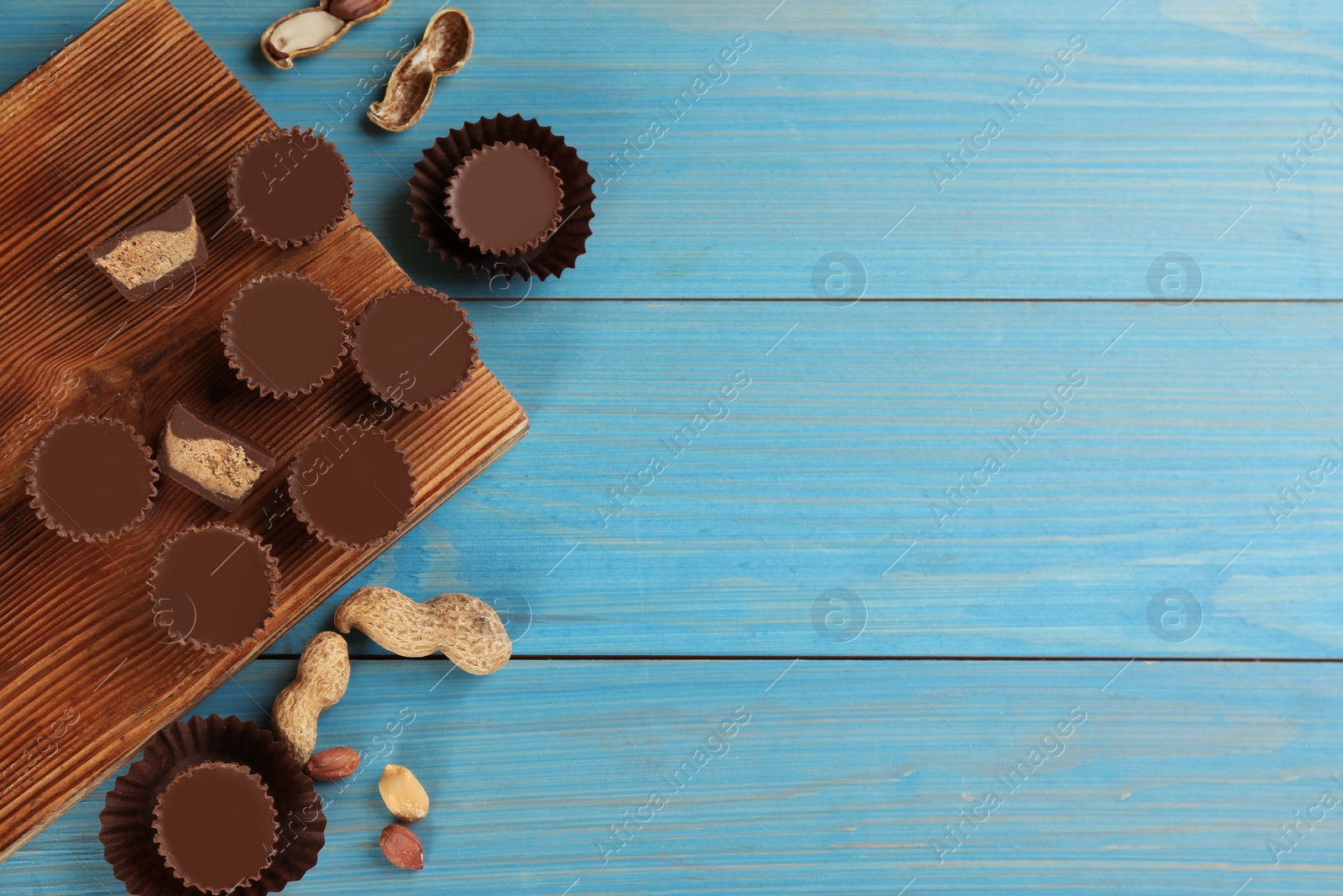 Photo of Flat lay composition with delicious peanut butter cups  on light blue wooden table, space for text