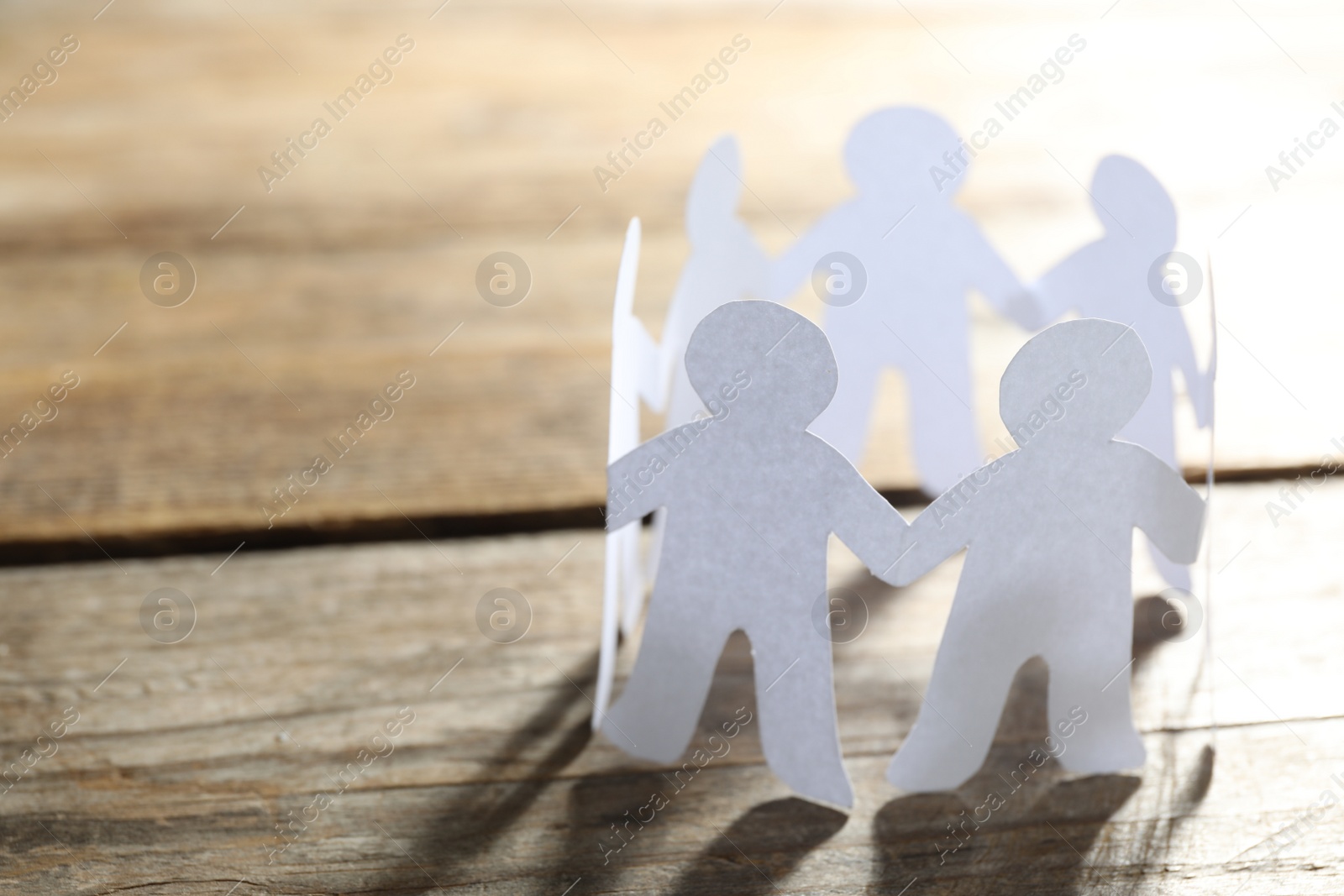 Photo of Paper people chain making circle on wooden background, space for text. Unity concept