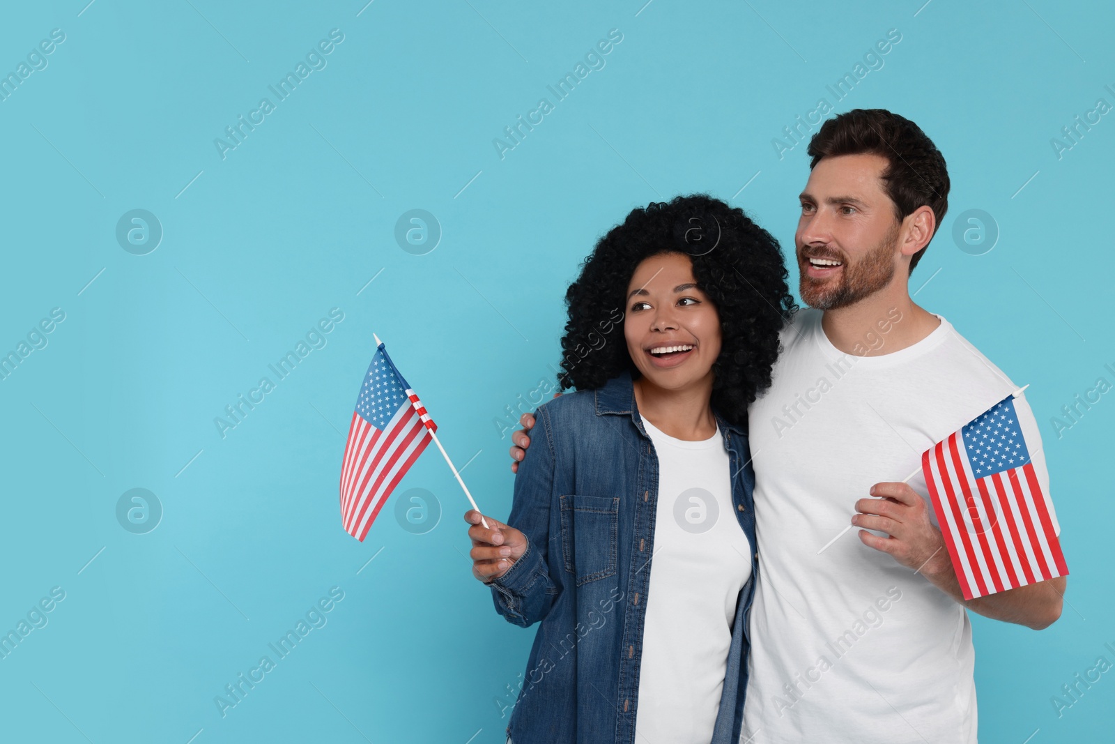 Photo of 4th of July - Independence Day of USA. Happy couple with American flags on light blue background, space for text