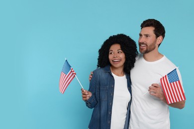 Photo of 4th of July - Independence Day of USA. Happy couple with American flags on light blue background, space for text