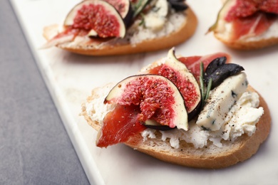 Photo of Sandwich with ripe fig, prosciutto and cheese on white board, closeup