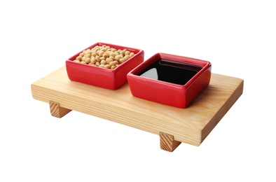 Wooden stand with dishes of soy sauce and beans on white background