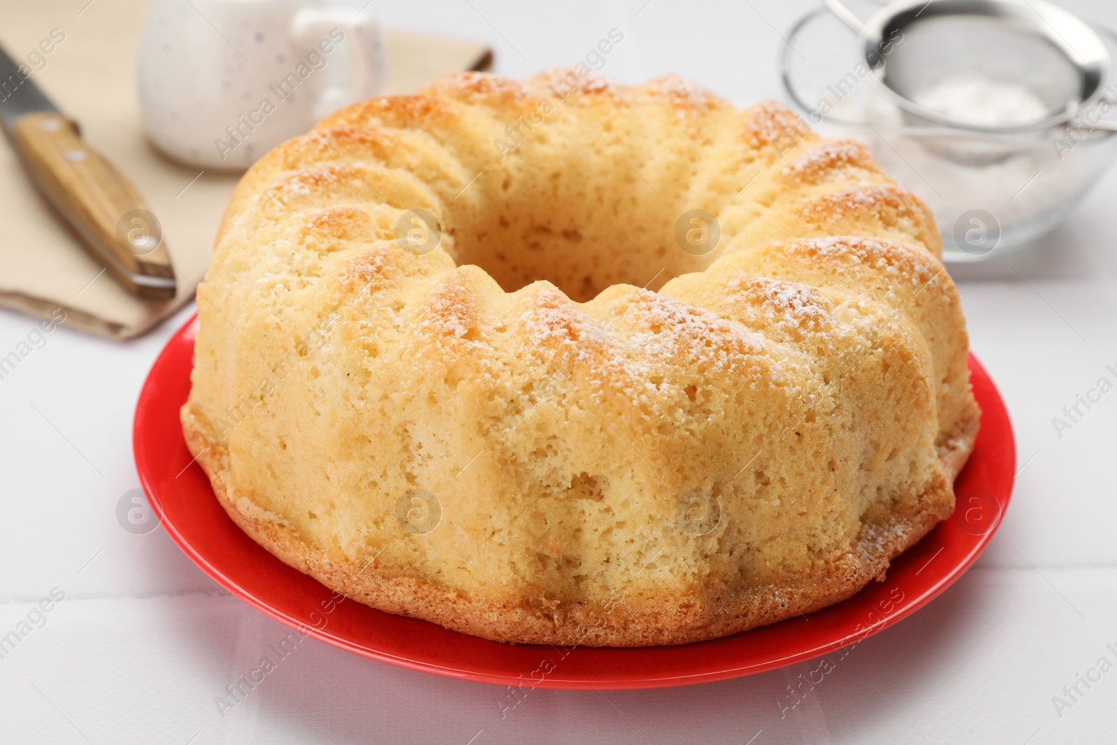 Photo of Delicious freshly baked sponge cake on white tiled table, closeup