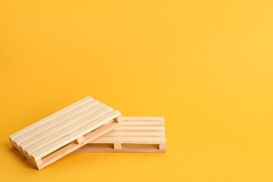 Wooden pallets on orange background, space for text