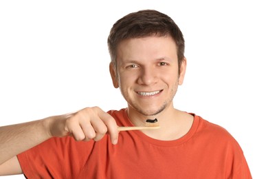 Photo of Man holding toothbrush with charcoal toothpaste on white background