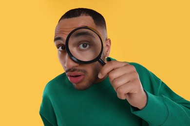 Photo of Man looking through magnifier glass on orange background