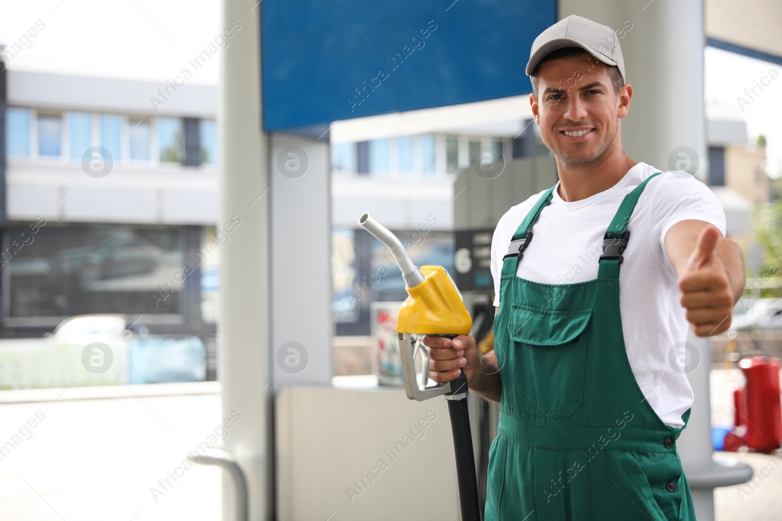 Photo of Worker with fuel pump nozzle at modern gas station