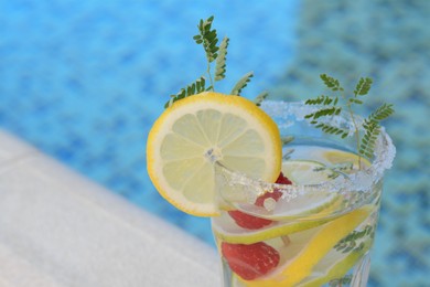 Photo of Delicious refreshing lemonade with raspberries near pool, closeup. Space for text