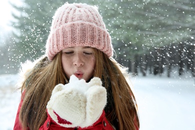 Photo of Teenage girl blowing snow in winter forest. Space for text