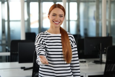 Photo of Happy woman welcoming and offering handshake in office