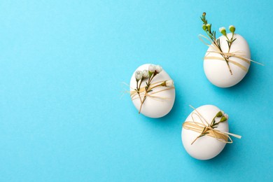 Photo of Festively decorated chicken eggs on light blue background, flat lay with space for text. Happy Easter