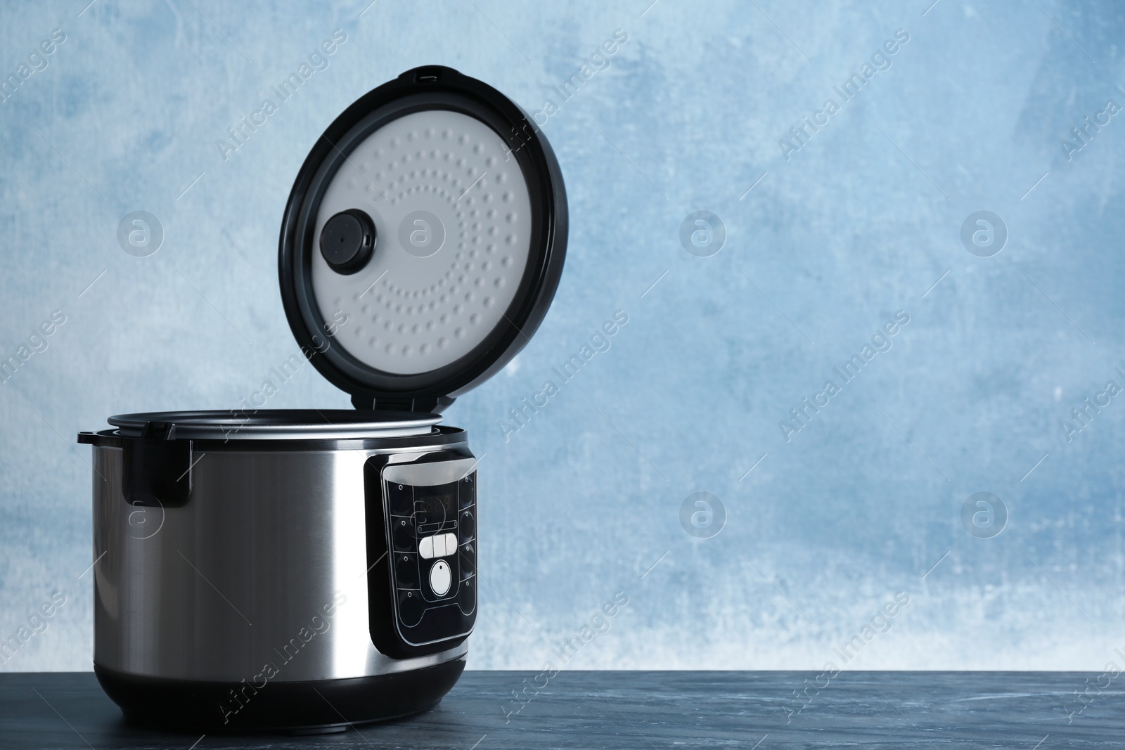 Photo of Modern powerful multi cooker on table against color background. Space for text