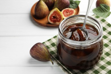 Photo of Jar of tasty sweet jam and fresh figs on white wooden table. Space for text